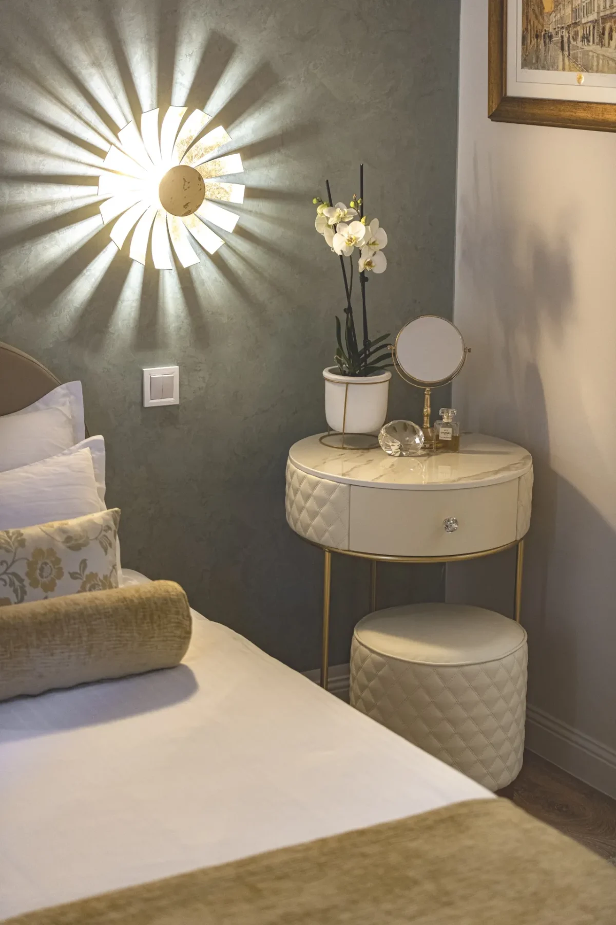 Gold sunburst wall lamp glowing above a quilted bedside table and orchid in a Dubrovnik boutique hotel room