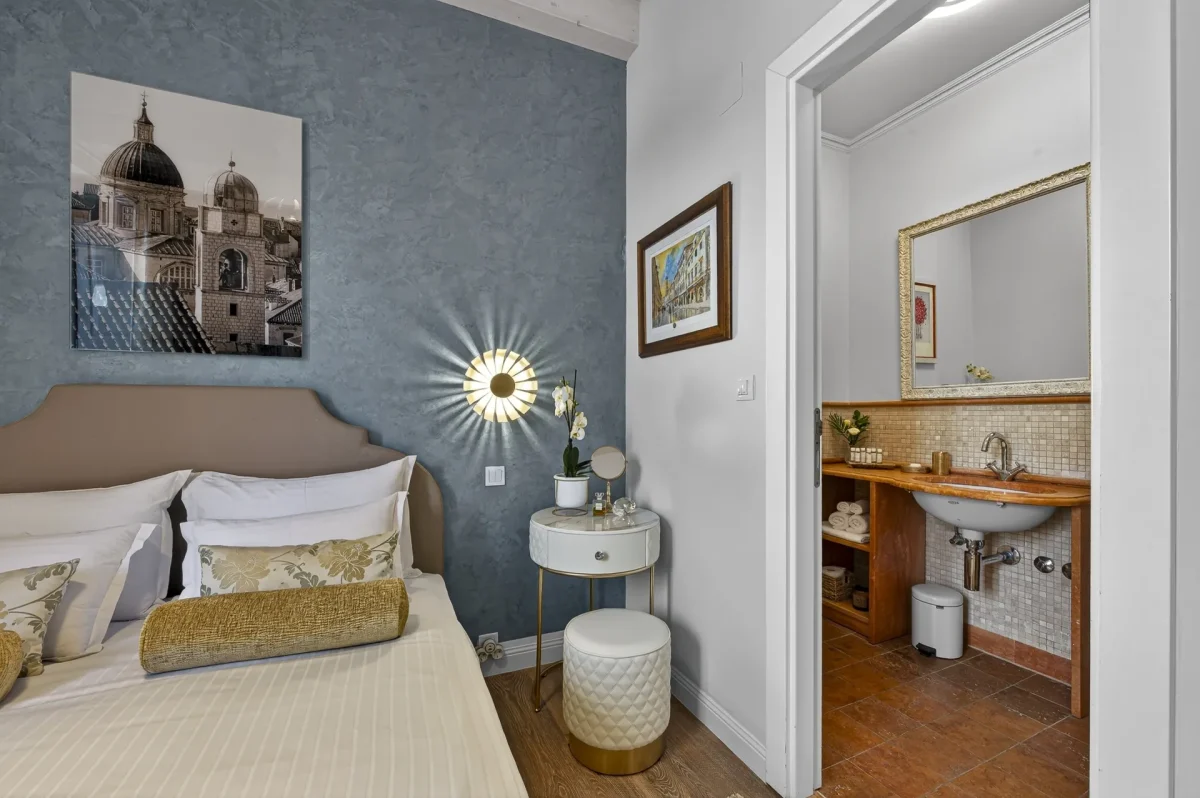 Double bed with Dubrovnik Cathedral print and open door to the en-suite bathroom in the Deluxe Double Room