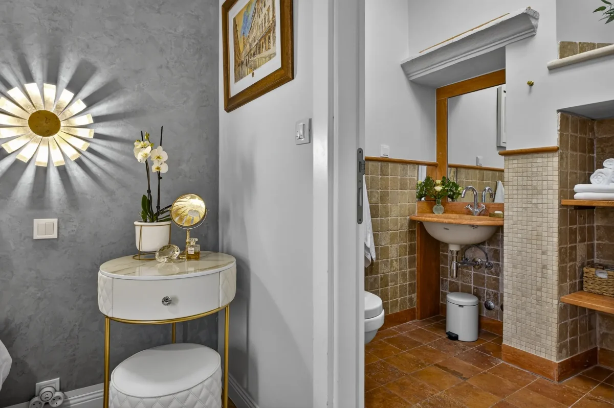 Orchid-topped bedside table next to the doorway of the tiled en-suite bathroom in the Deluxe Double Room