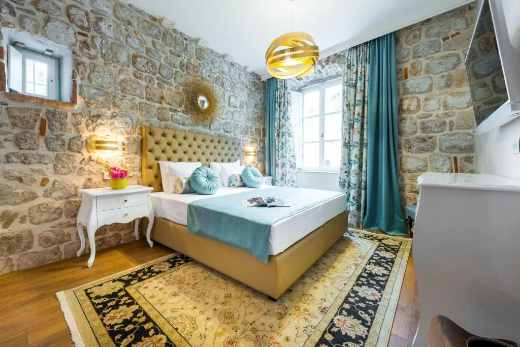 Double room at Dominus Rooms in Dubrovnik Old Town with exposed stone walls and teal curtains