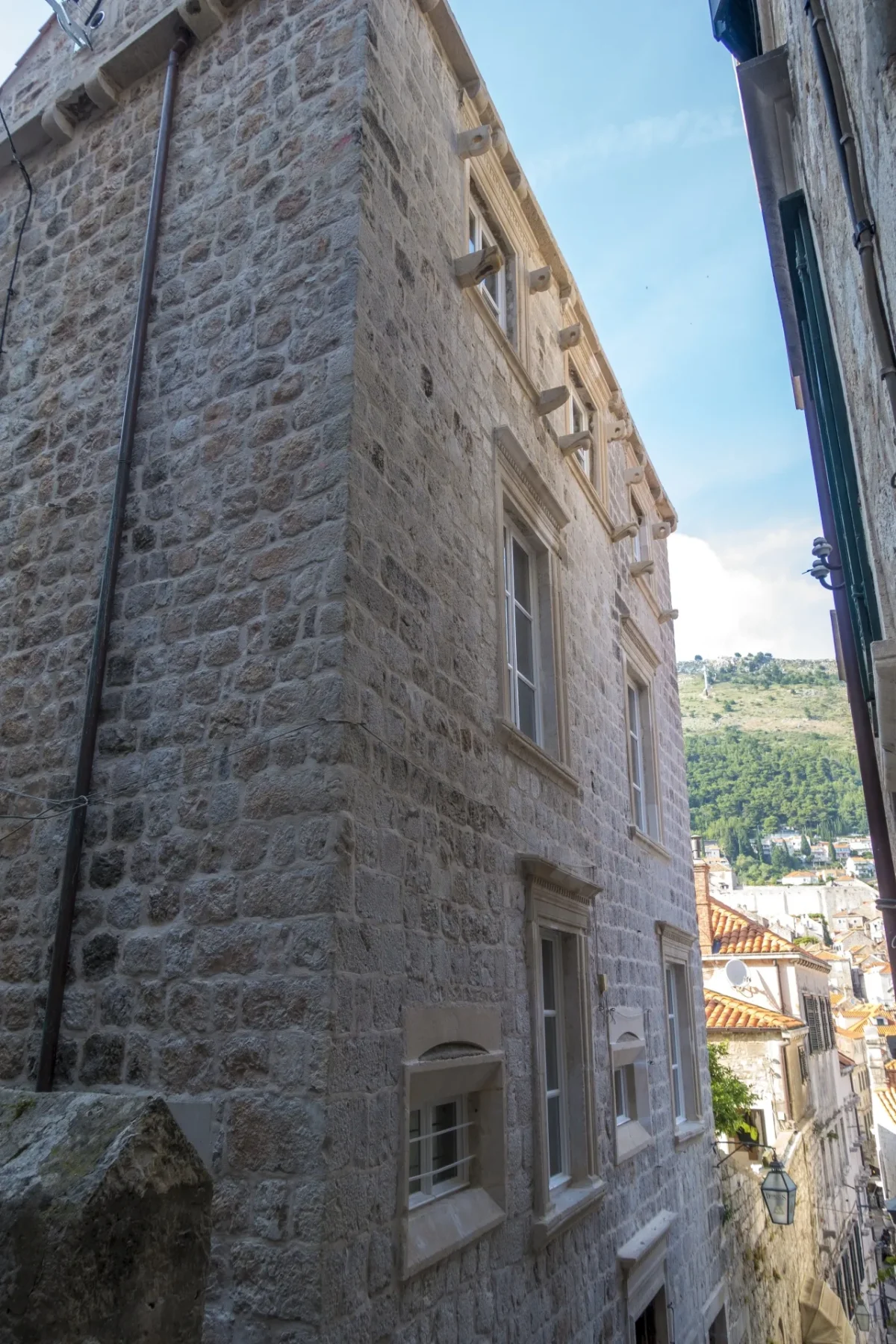 Tall stone exterior of Dominus Little Palace with carved window frames, on a quiet lane in Dubrovnik Old Town