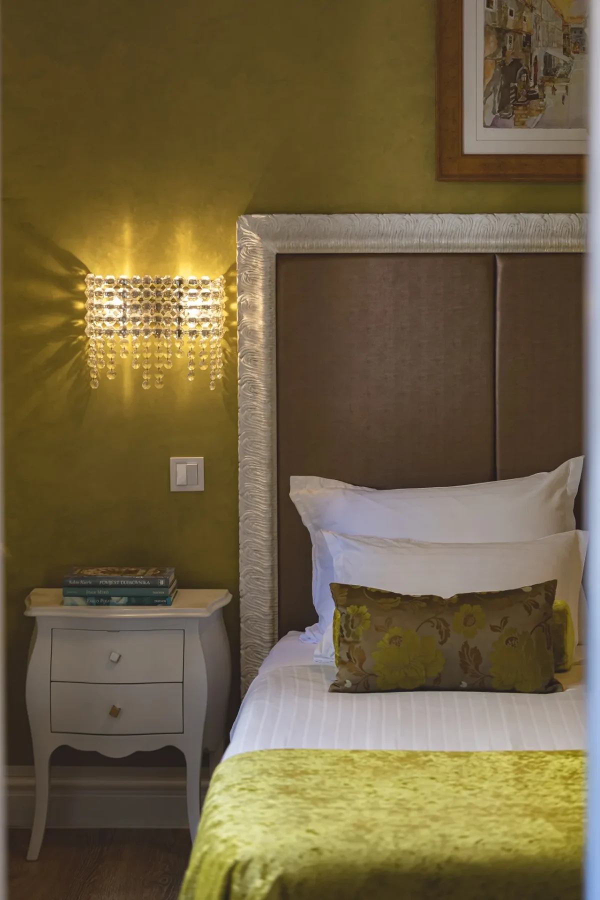 Upholstered headboard, crystal wall sconce and white bedside table in the Executive Suite bedroom