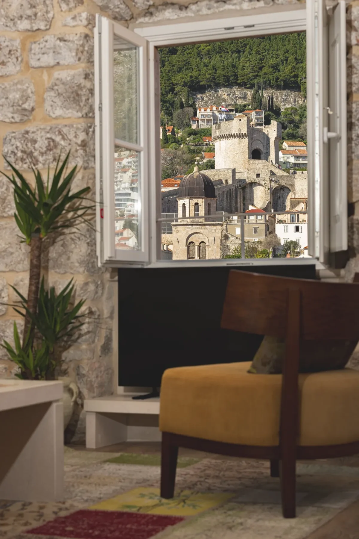 Armchair and potted palm beside an open window with views of Minčeta Tower from the Executive Suite