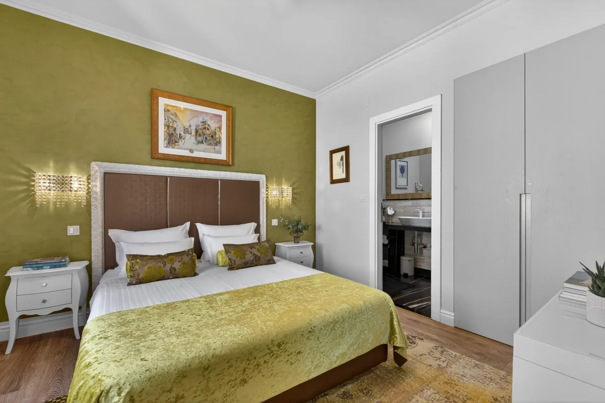 Executive Suite bedroom at Dominus Little Palace with olive-green feature wall, padded headboard and crystal sconces