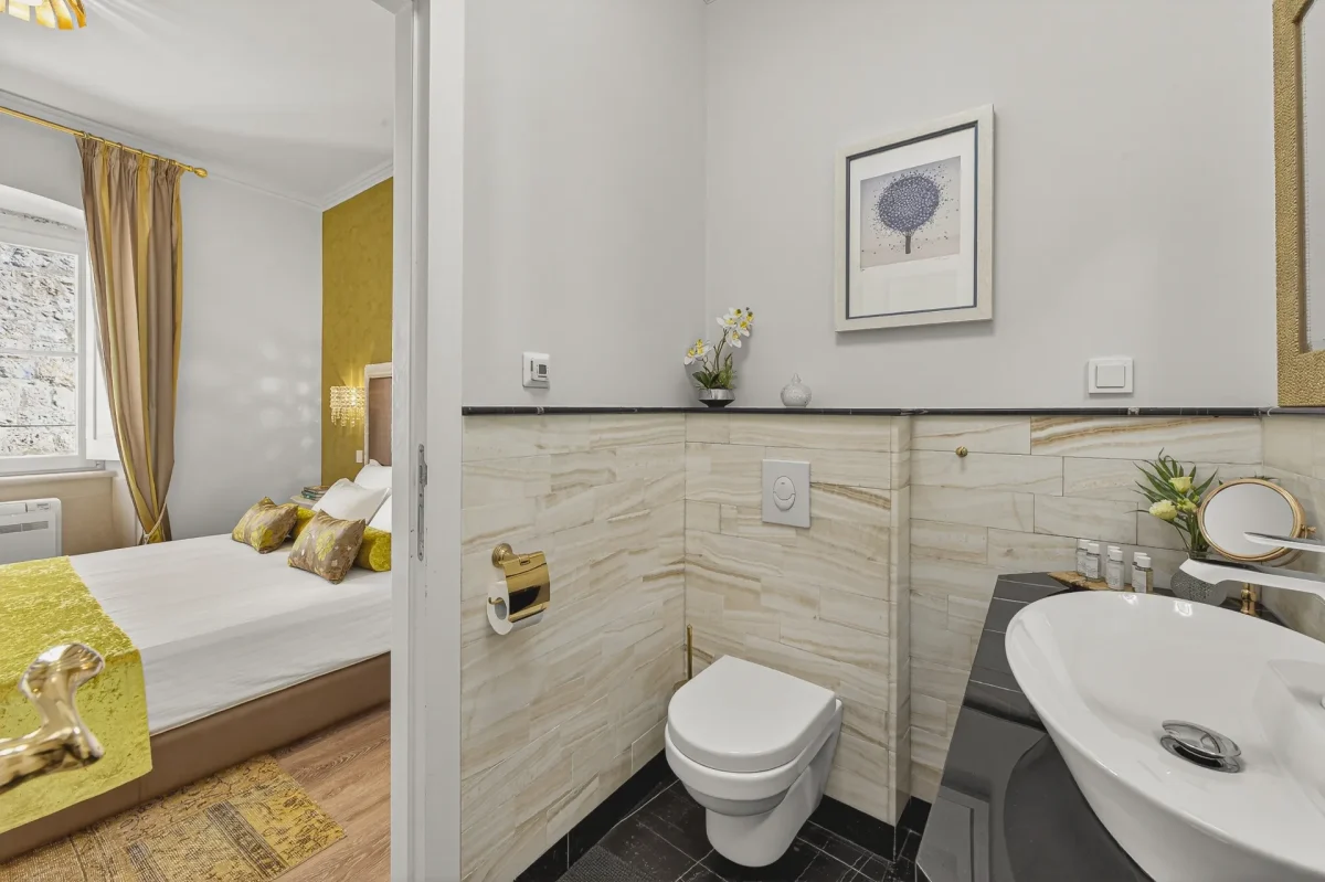 Executive Suite bathroom with wall-hung toilet and gold accessories, opening onto the bedroom